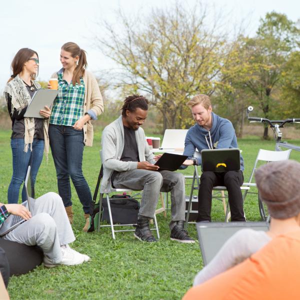 Image of people on laptops in the park with chairs and bikes