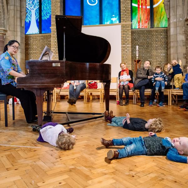 toddlers lie on the floor next to a bach to baby pianist